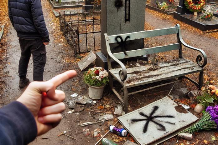 Sugadinta kapavietė su sulaužytu suoliuku ir vandalizmo požymiais kapinėse.