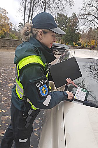 Policijos pareigūnė patikrina automobilius ir informuoja vairuotojus apie saugumo priemones Visų Šventųjų dienų laikotarpiu.