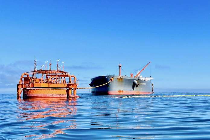 Tanklaivis ir plūduriuojantis naftos perkrovimo terminalas ramiame jūros vandenyje.